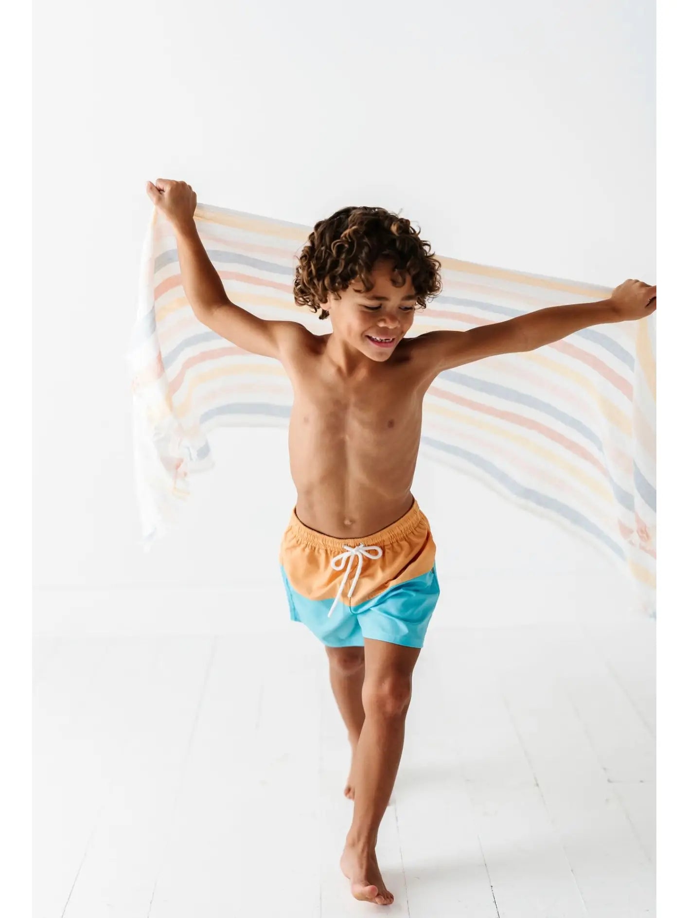 boy running with towel wearing swim trunks