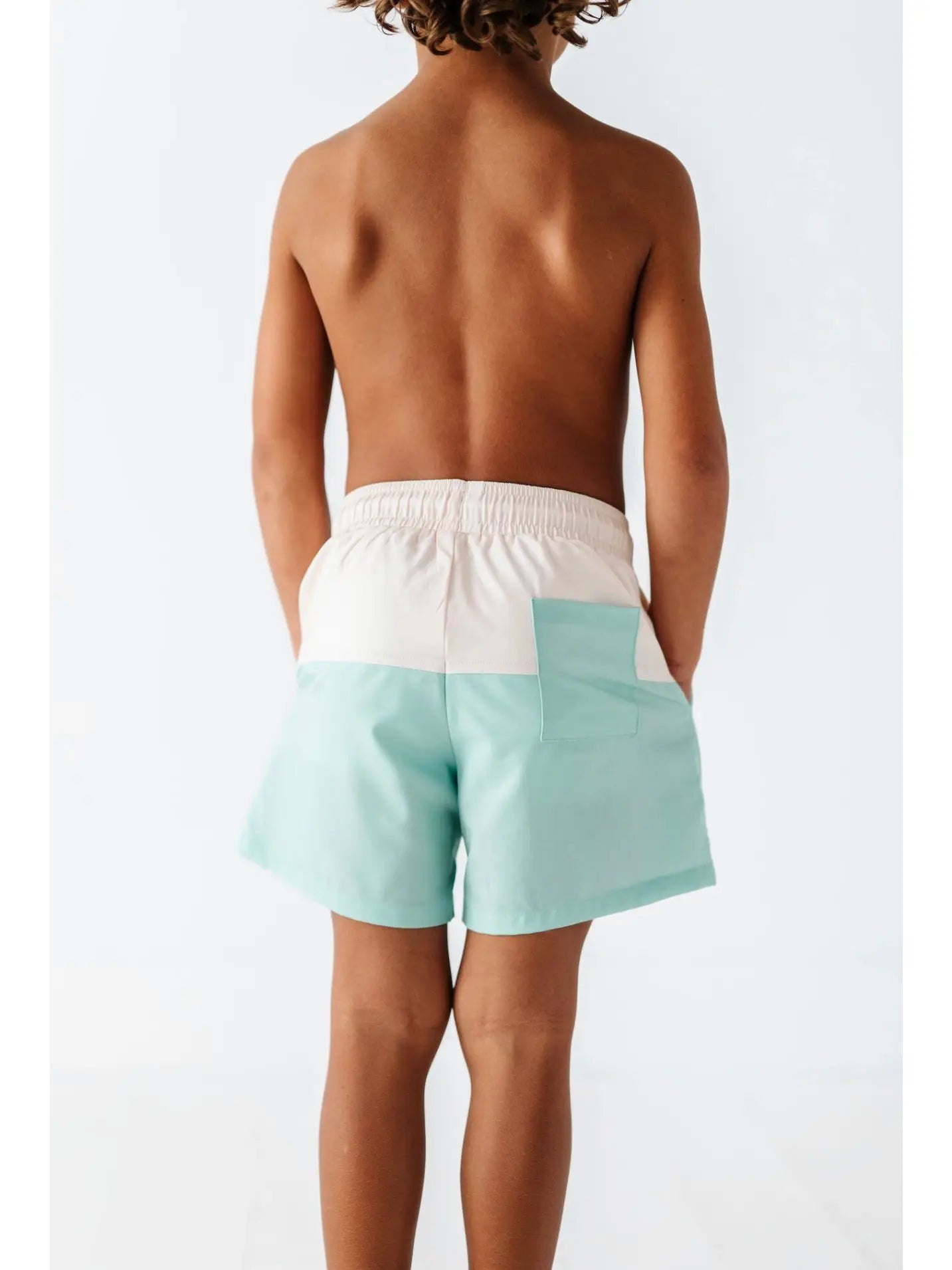 boy wearing swim shorts that are green and cream color with pockets