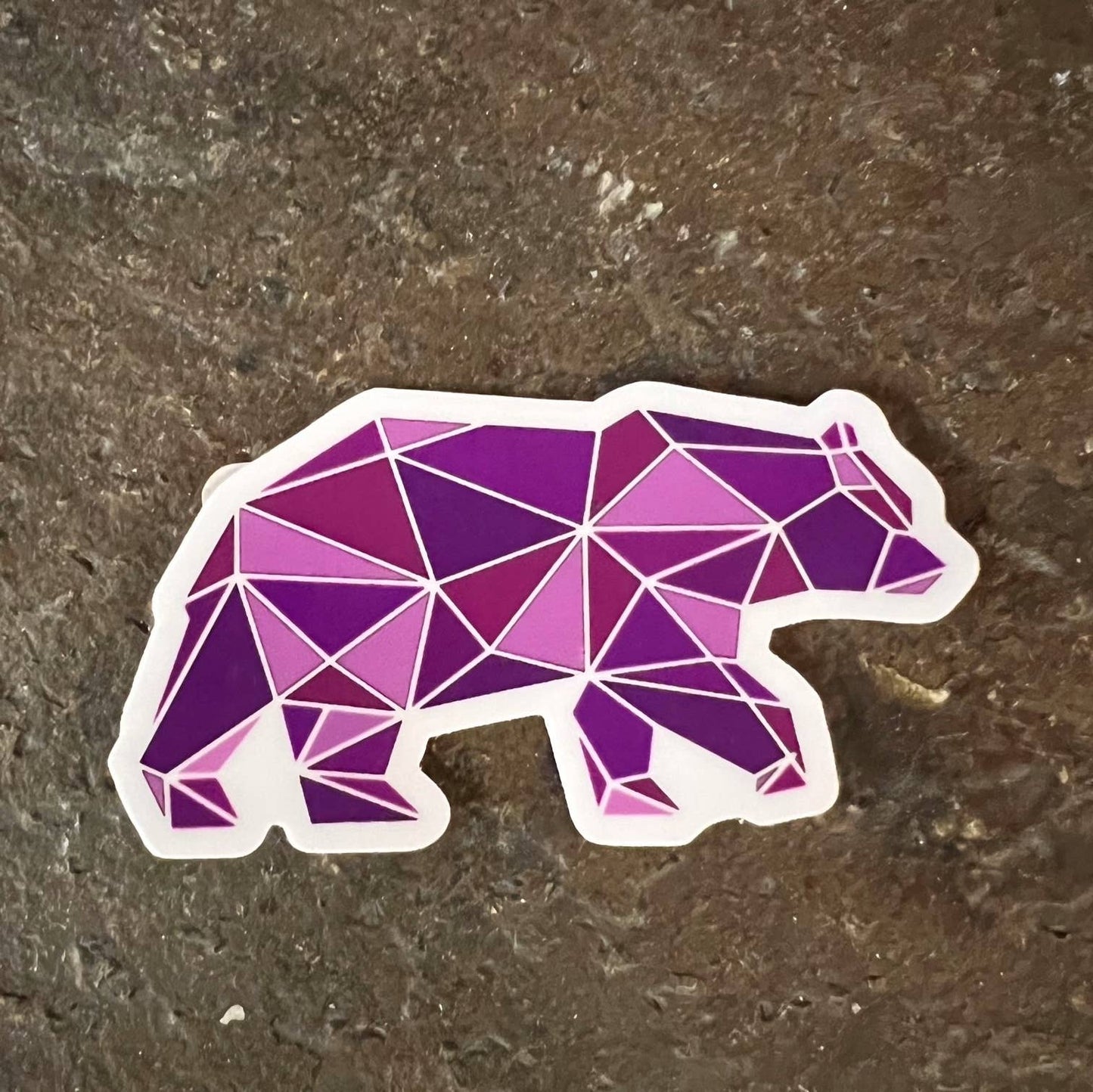 Geometric purple bear sticker on a textured surface