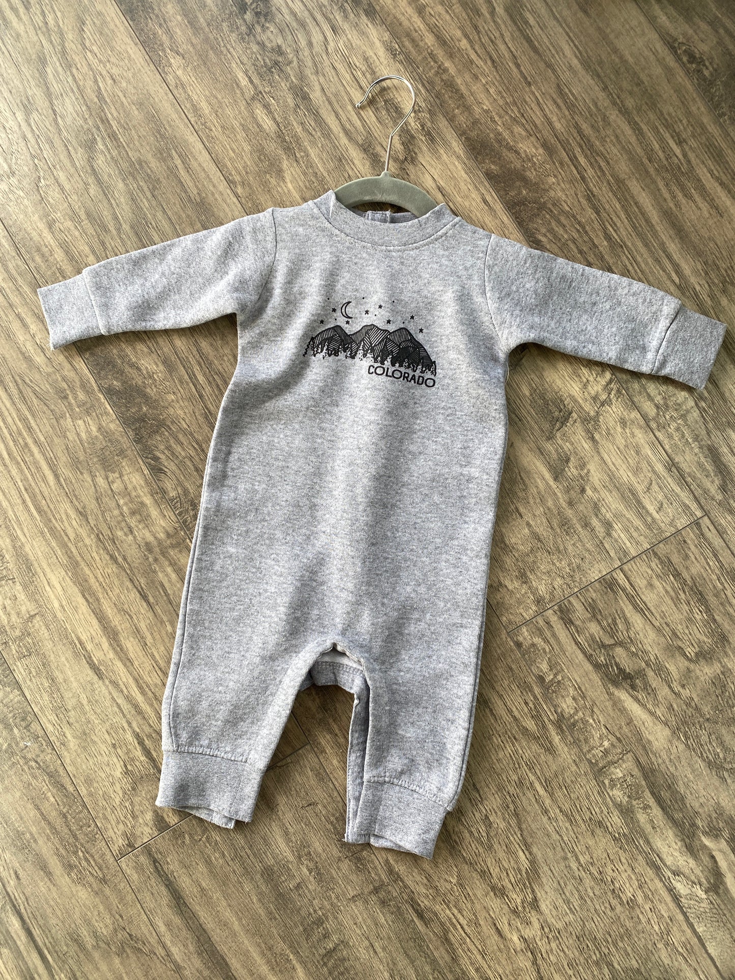 light grey baby bodysuit with colorado mountains and night sky graphic
