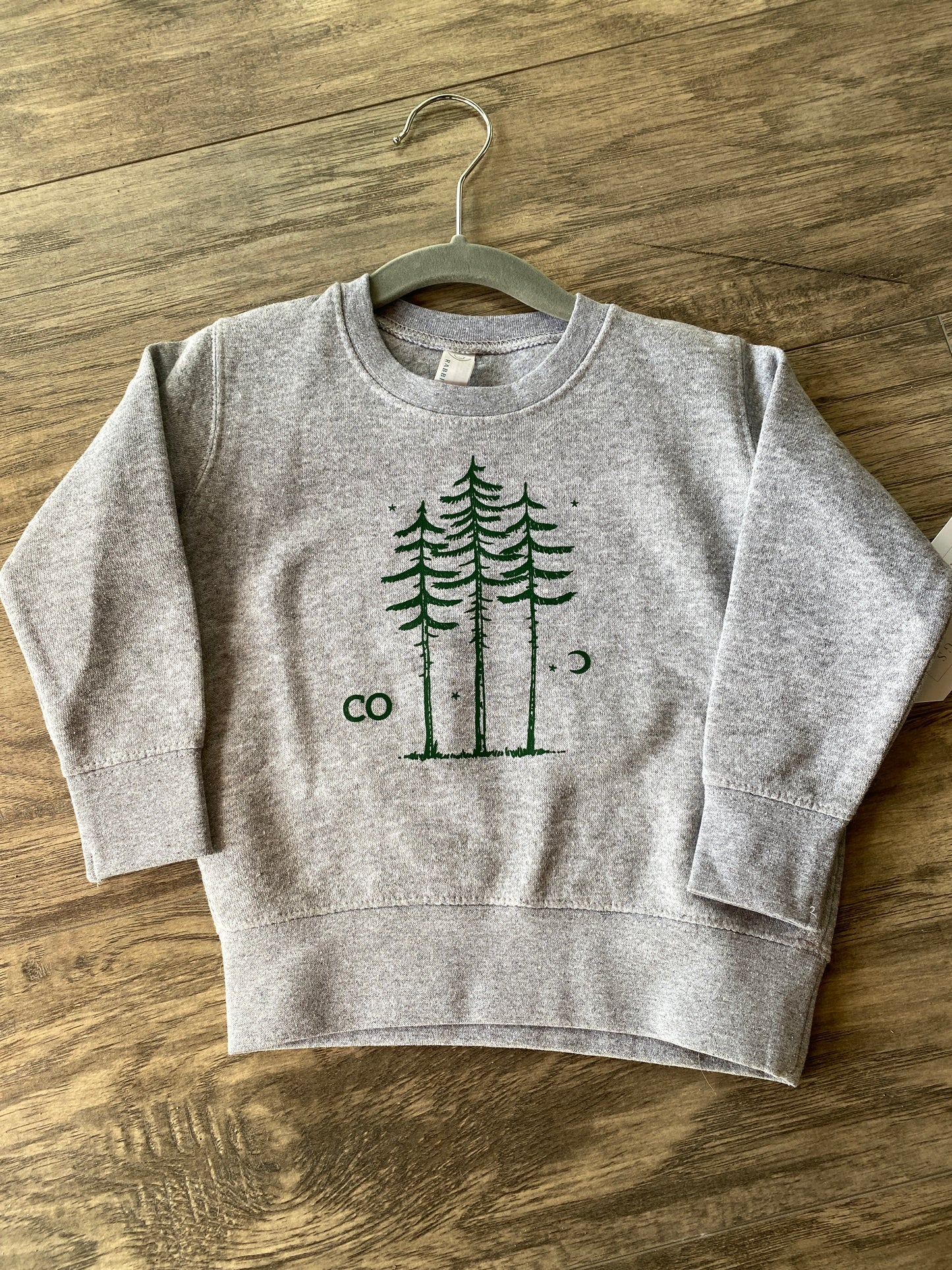 light grey children's sweatshirt with three pine trees and a moon on it