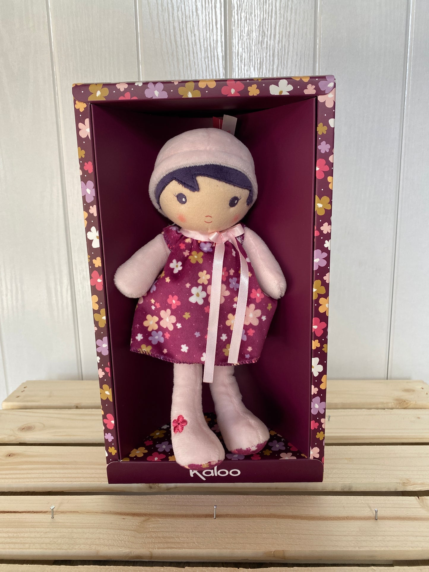 soft plush toy doll with dark hair and purple dress with flowers