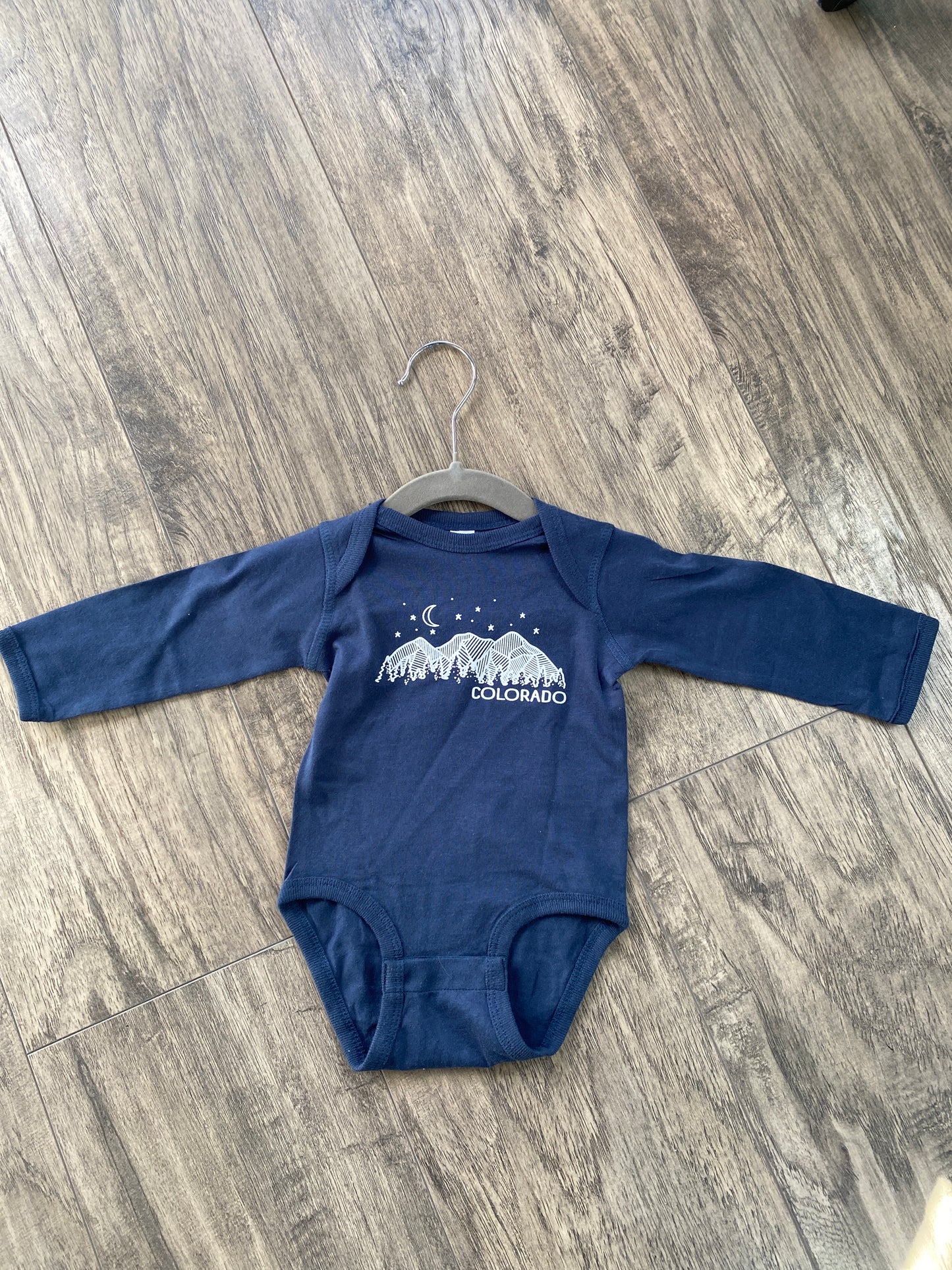 navy blue long sleeve baby onesie with Colorado mountains and forest graphic