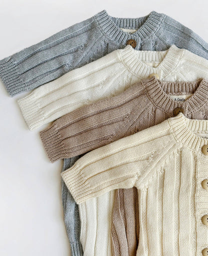 Four knitted sweaters in gray, white, brown, and beige on a light background