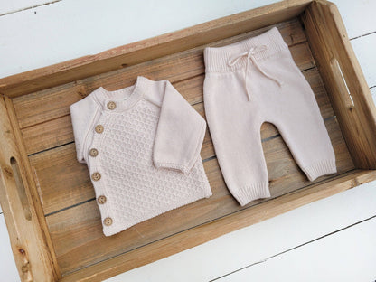 Baby sweater and pants set on a wooden tray with a white background