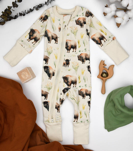 Baby romper with animal print surrounded by baby items on a white background