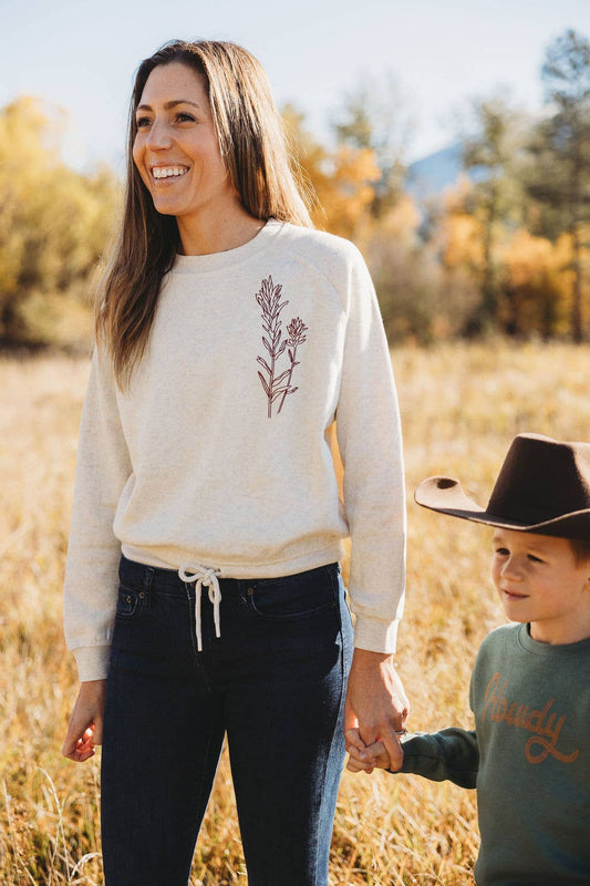 Woman and child holding hands in a field with a nature-themed sweater
