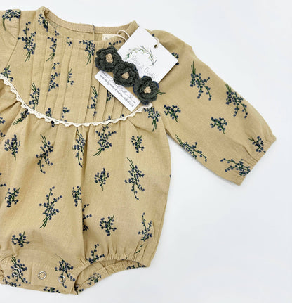 Beige baby romper with floral pattern on a white background