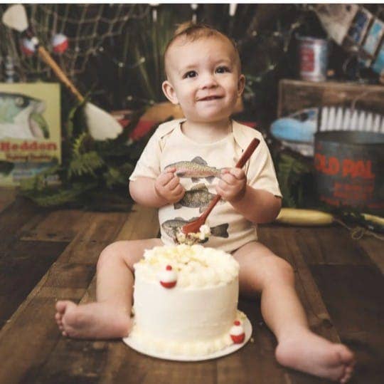 Child sitting with a cake and fishing-themed background