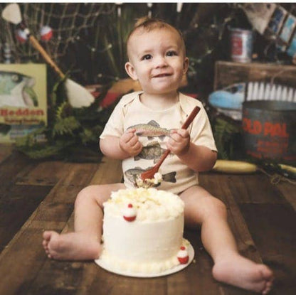 Child sitting with a cake and fishing-themed background