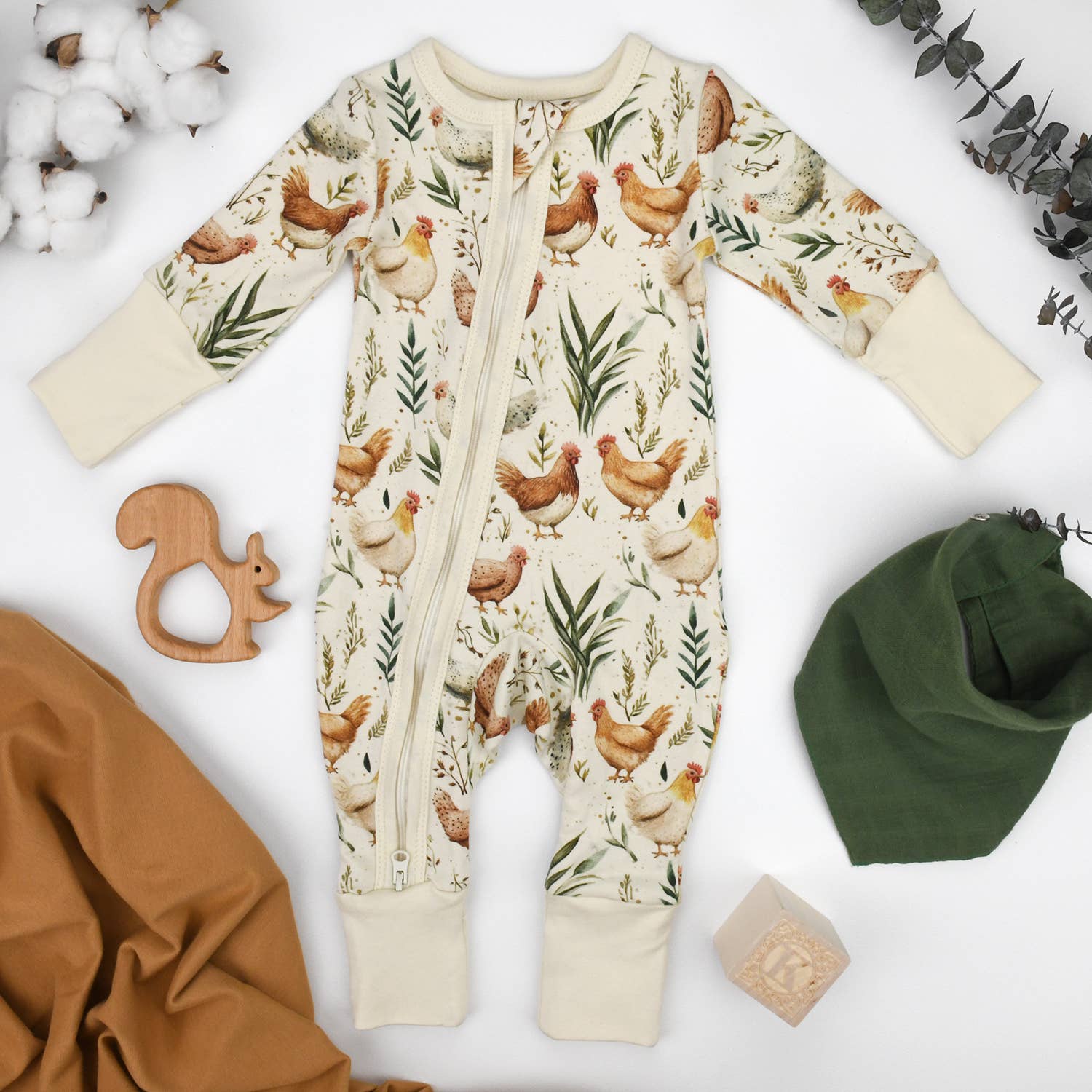 Baby romper with chicken pattern on a white background with accessories.