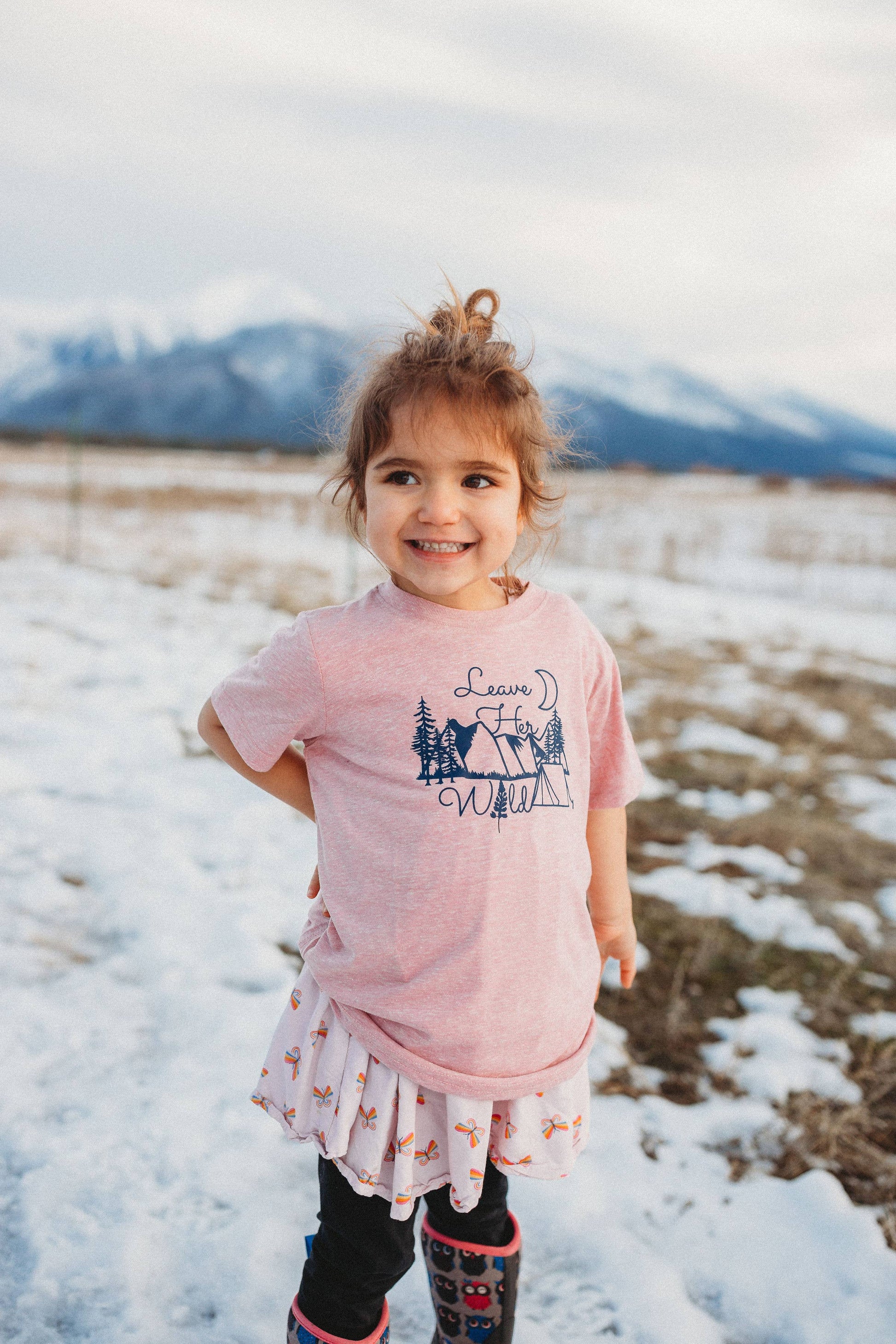 girl wearing an outdoors theme pink t-shirt with "leave her wild" graphic 