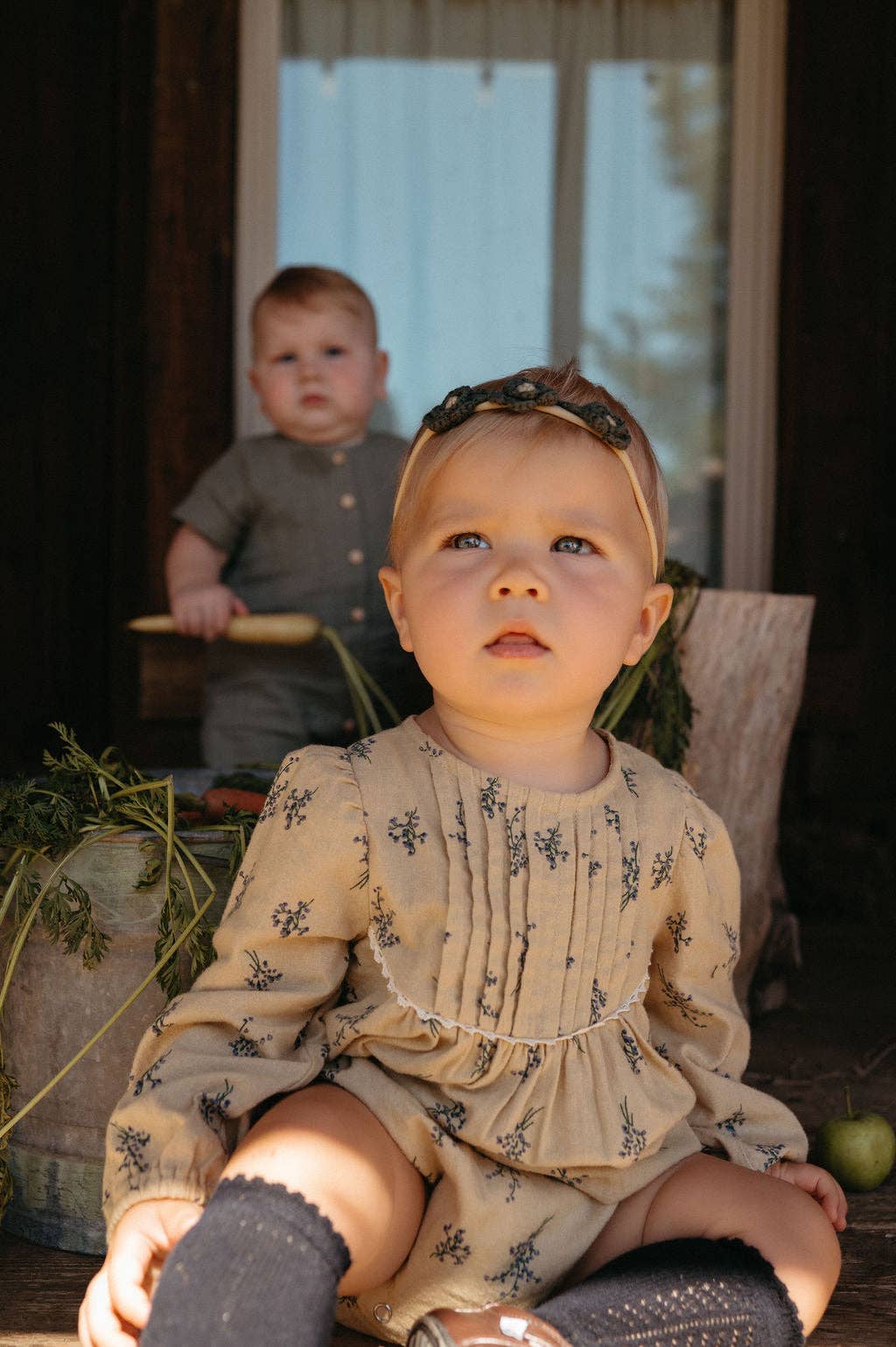 Two children sitting outdoors with a blurred background