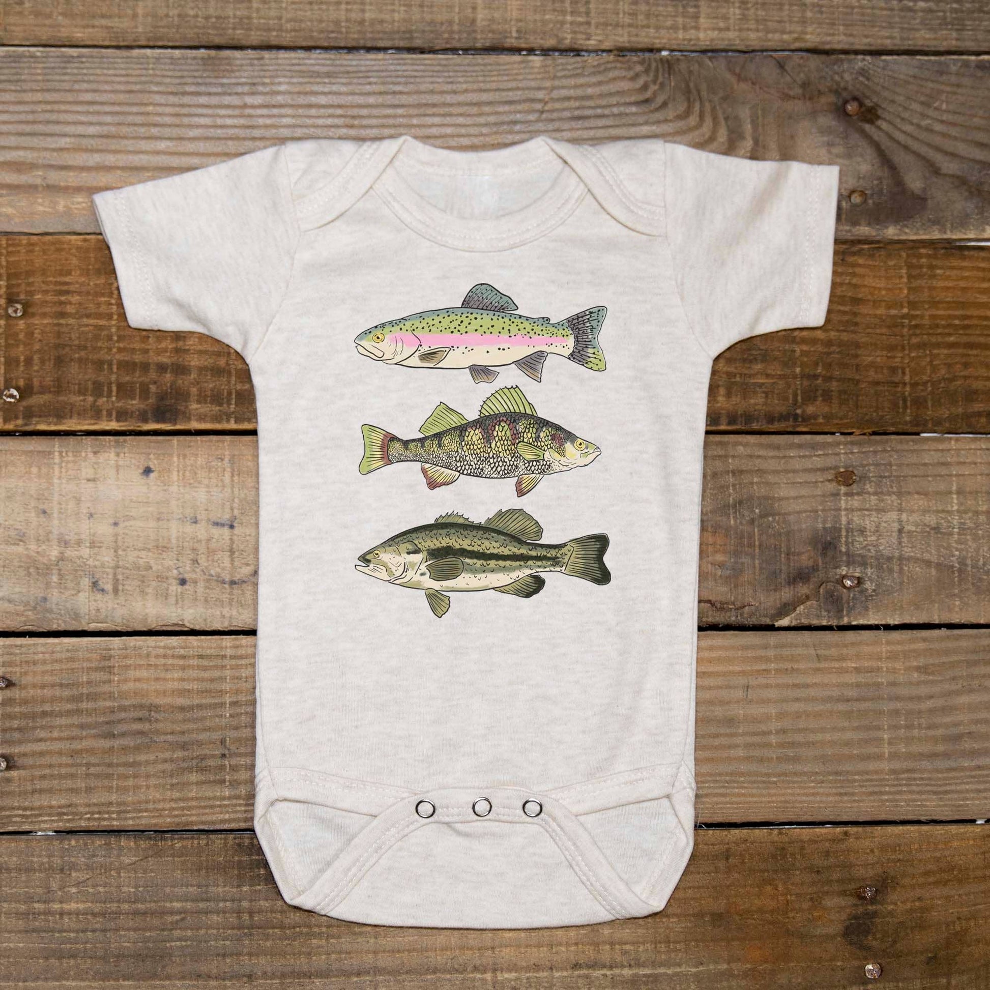 White baby onesie with fish illustrations on a wooden surface
