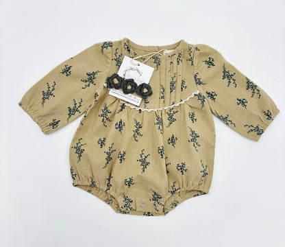 Beige baby romper with black floral pattern on a white background